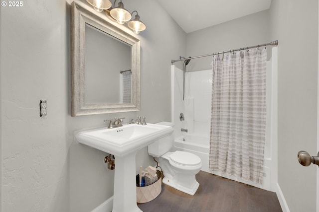 bathroom featuring toilet, wood finished floors, shower / tub combo with curtain, and a sink