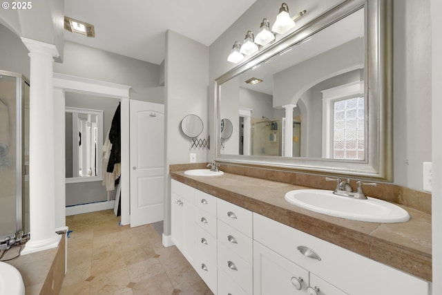 full bath featuring a sink, a shower stall, and decorative columns