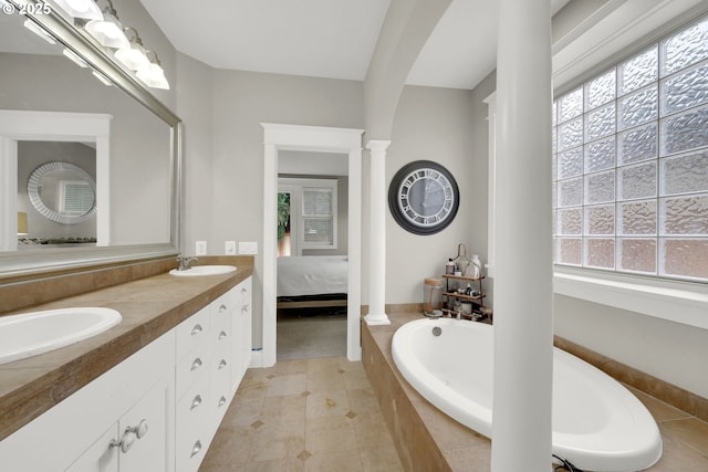 ensuite bathroom with a sink, a healthy amount of sunlight, and decorative columns