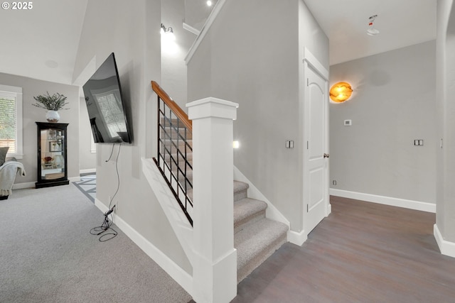 stairway featuring baseboards and a high ceiling