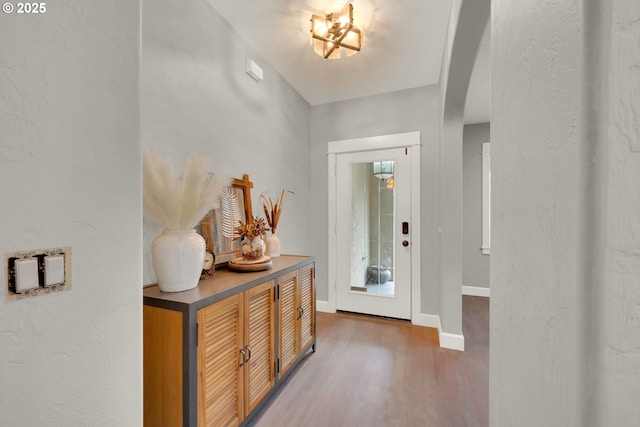 entryway with baseboards, arched walkways, and wood finished floors