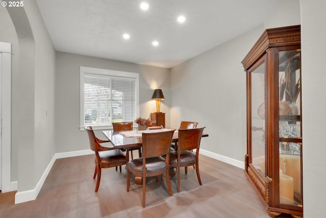 dining area with recessed lighting, baseboards, arched walkways, and wood finished floors