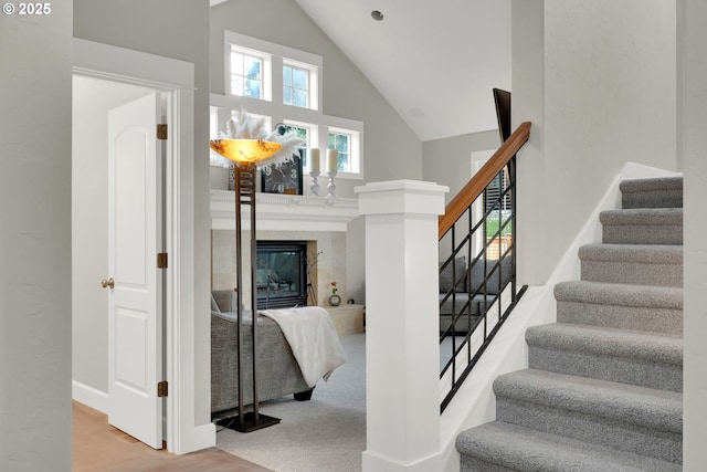 stairs with a fireplace and high vaulted ceiling