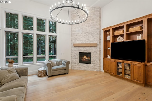 9423 NE 180th Way, Battle Ground, WA 98604 - living area featuring a towering ceiling, a chandelier, light wood-type flooring, and a stone fireplace