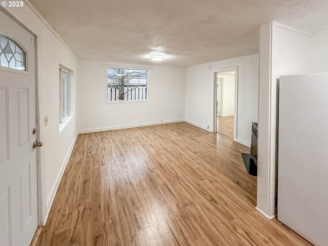 foyer entrance with a textured ceiling and light hardwood / wood-style floors