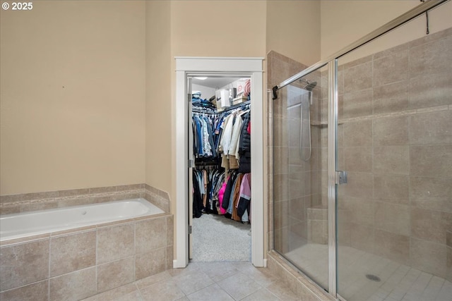 full bath with tile patterned flooring, a walk in closet, a bath, and a stall shower