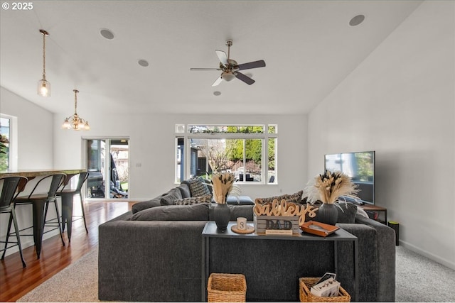 living area featuring a wealth of natural light, ceiling fan with notable chandelier, baseboards, and vaulted ceiling