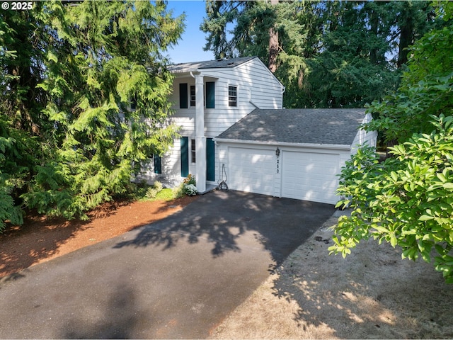 view of front of house with a garage, driveway, and a shingled roof