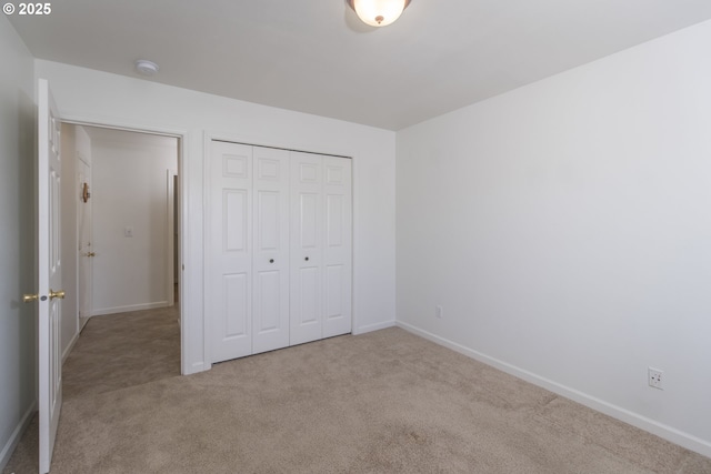 unfurnished bedroom featuring light colored carpet and a closet