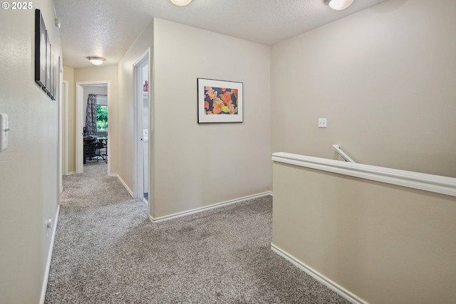 hall with light colored carpet and a textured ceiling