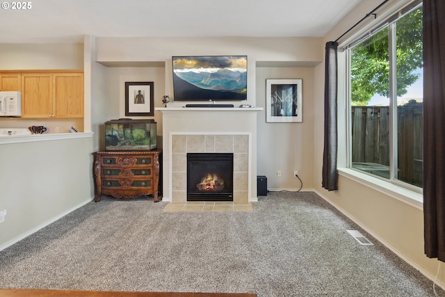 unfurnished living room with a tiled fireplace and carpet floors