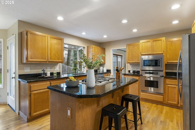 kitchen with a breakfast bar area, a center island, light wood-style floors, and stainless steel appliances