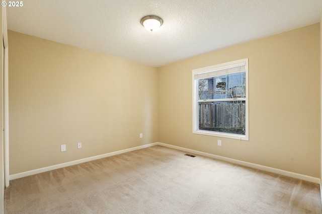 carpeted spare room with visible vents, a textured ceiling, and baseboards