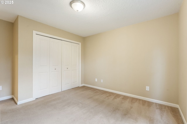 unfurnished bedroom featuring a closet, baseboards, a textured ceiling, and carpet flooring