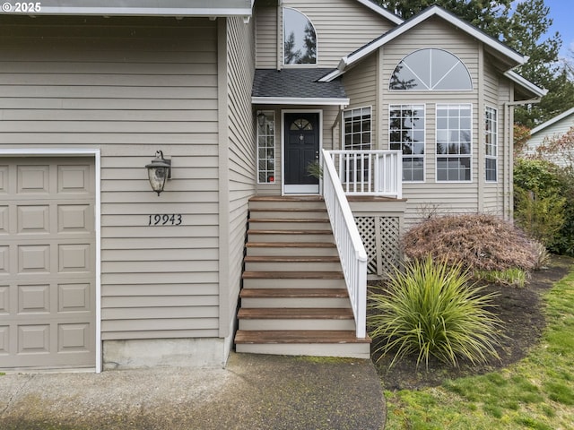 entrance to property featuring roof with shingles and an attached garage