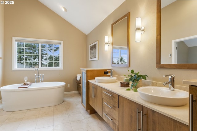 bathroom featuring a sink, a soaking tub, double vanity, and vaulted ceiling