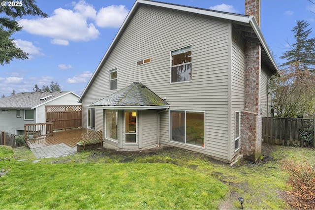 rear view of property featuring a yard, a wooden deck, a chimney, and fence