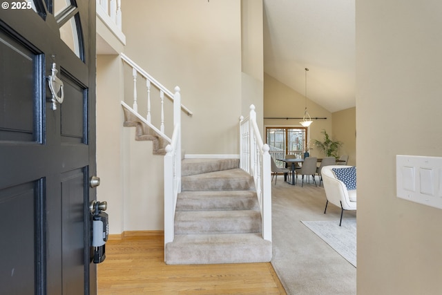 foyer entrance with stairway, high vaulted ceiling, and wood finished floors