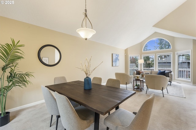 dining room featuring baseboards, light colored carpet, and high vaulted ceiling