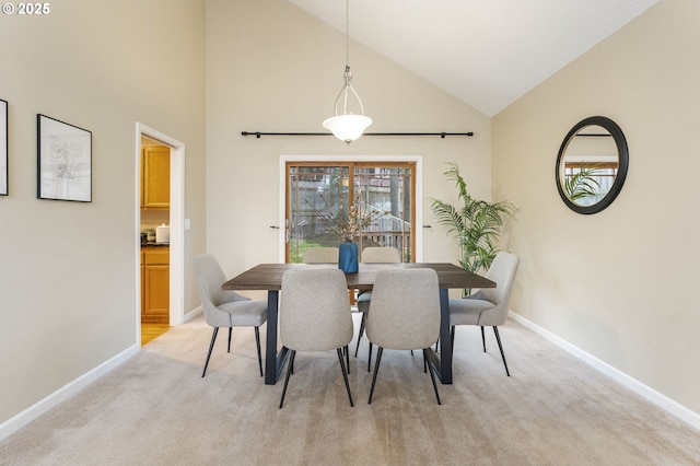 dining space with baseboards, light colored carpet, and high vaulted ceiling