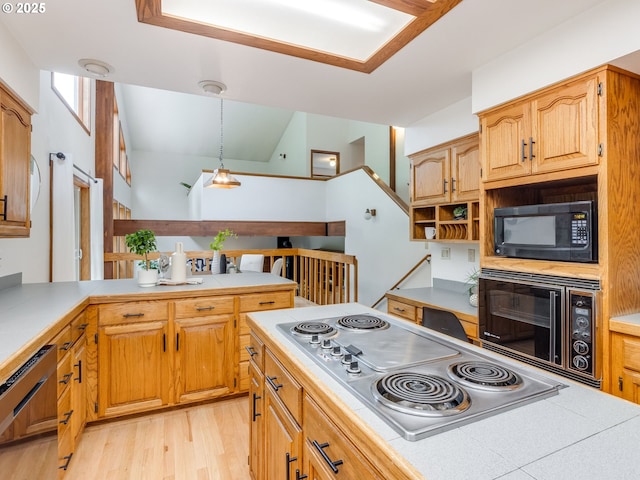 2972 Tolkien Ln, Lake Oswego, OR 97034 - kitchen with black microwave, stainless steel electric cooktop, light countertops, light wood-style flooring, and decorative light fixtures