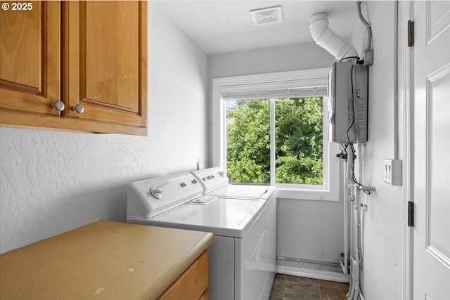 laundry area with visible vents, cabinet space, water heater, separate washer and dryer, and a textured wall