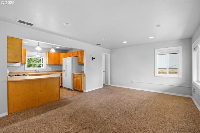 kitchen featuring light colored carpet, visible vents, baseboards, open floor plan, and white appliances