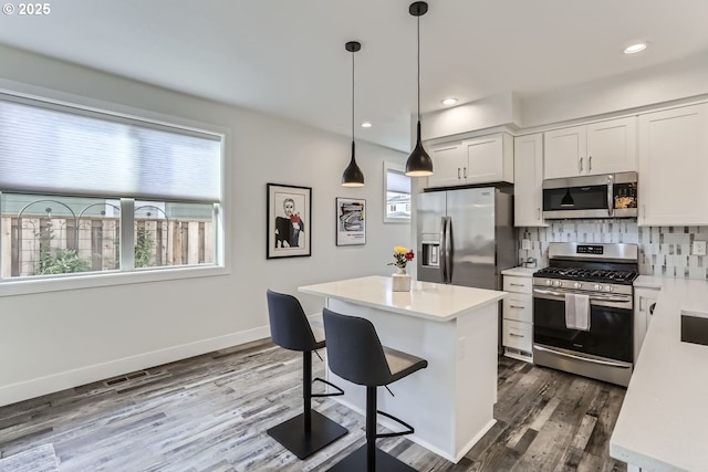 kitchen with white cabinetry, a center island, pendant lighting, stainless steel appliances, and backsplash