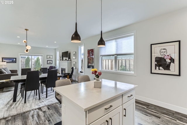 kitchen featuring white cabinetry, wood-type flooring, a center island, and decorative light fixtures