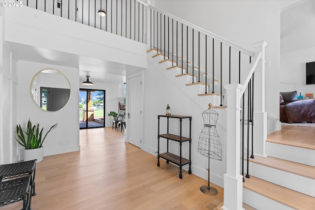 staircase with wood finished floors, a towering ceiling, and baseboards