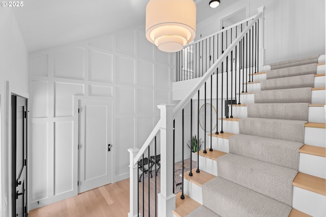 stairs with a decorative wall and wood finished floors