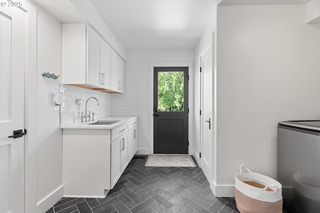 washroom featuring cabinet space, baseboards, and brick patterned flooring