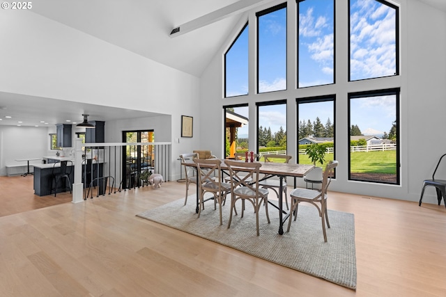 dining area with high vaulted ceiling and wood finished floors