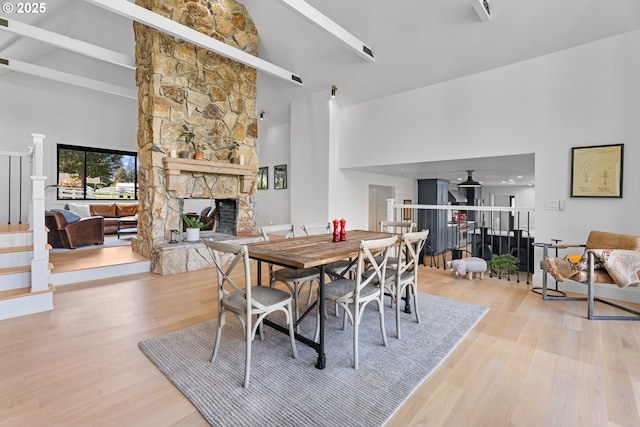 dining area with a fireplace, high vaulted ceiling, and wood finished floors