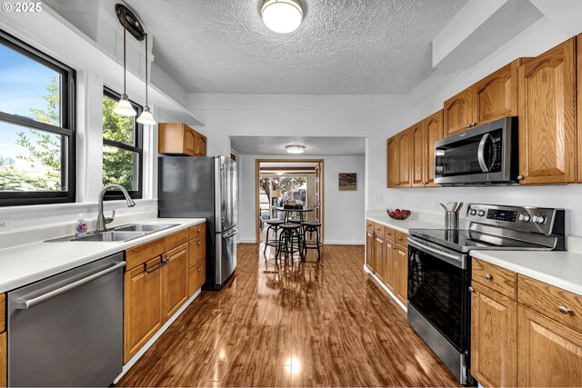 6206 N Denver Ave, Portland, OR 97217 - kitchen with appliances with stainless steel finishes, a sink, dark wood-type flooring, a textured ceiling, and light countertops
