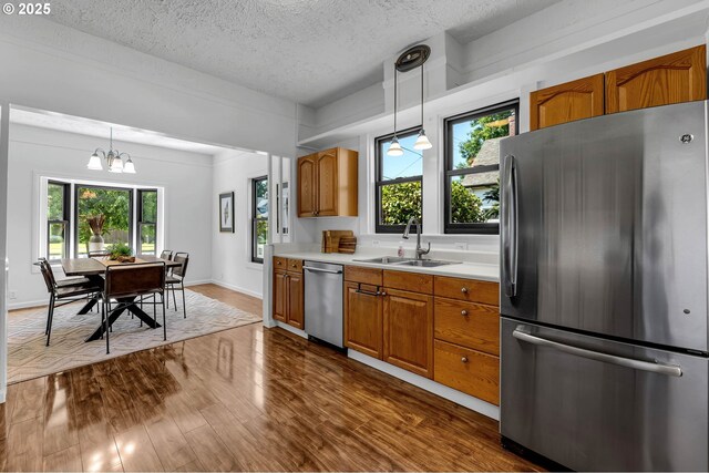 6206 N Denver Ave, Portland, OR 97217 - kitchen featuring appliances with stainless steel finishes, a sink, brown cabinetry, dark wood-style flooring, and light countertops
