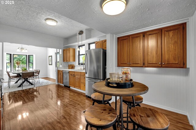 6206 N Denver Ave, Portland, OR 97217 - kitchen featuring stainless steel appliances, dark wood-type flooring, baseboards, brown cabinetry, and a textured ceiling