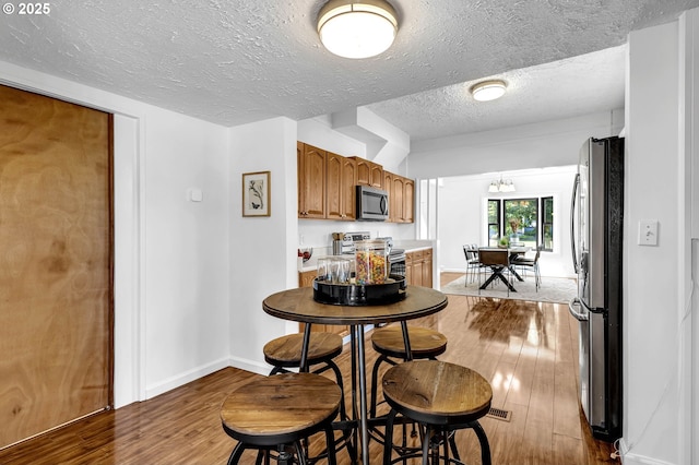 6206 N Denver Ave, Portland, OR 97217 - dining area featuring wood finished floors, a textured ceiling, and baseboards