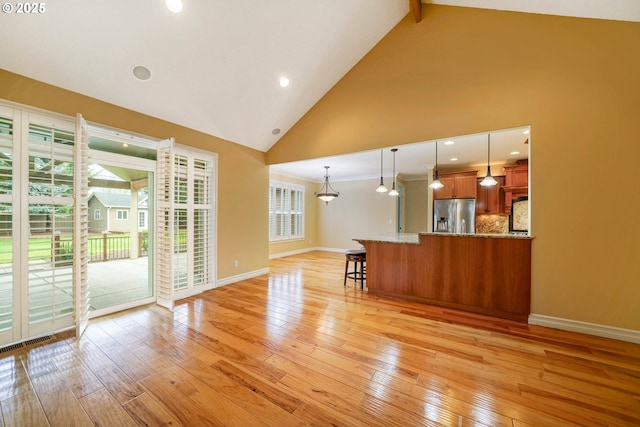 unfurnished living room featuring high vaulted ceiling and light hardwood / wood-style flooring