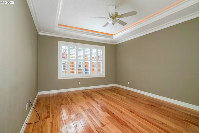 spare room featuring crown molding, a textured ceiling, a tray ceiling, ceiling fan, and light hardwood / wood-style floors