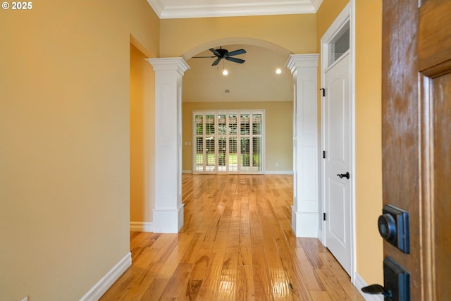 corridor featuring ornamental molding, decorative columns, and light wood-type flooring