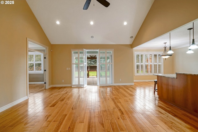 unfurnished living room with light hardwood / wood-style flooring, high vaulted ceiling, and a healthy amount of sunlight