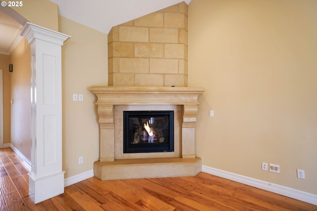 details featuring wood-type flooring, decorative columns, and a large fireplace