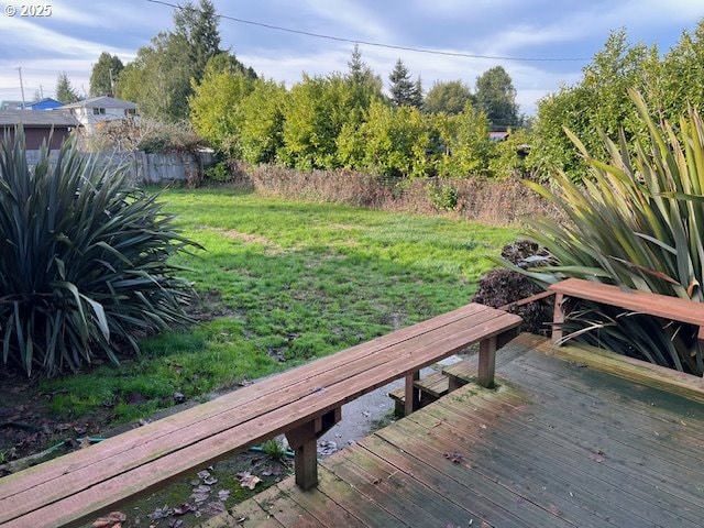 view of dock featuring a wooden deck, a lawn, and fence