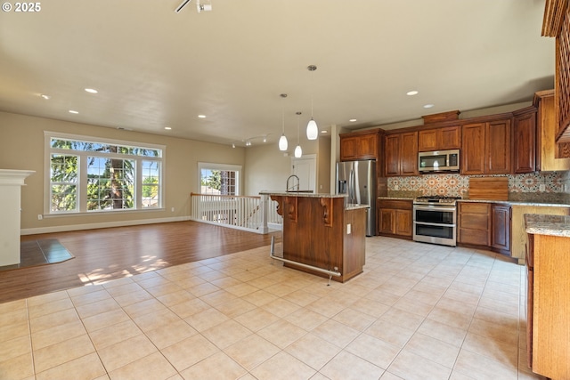 1748 Hardin Ave NW, Salem, OR 97304 - kitchen featuring stainless steel appliances, a breakfast bar, light tile patterned floors, tasteful backsplash, and light stone countertops