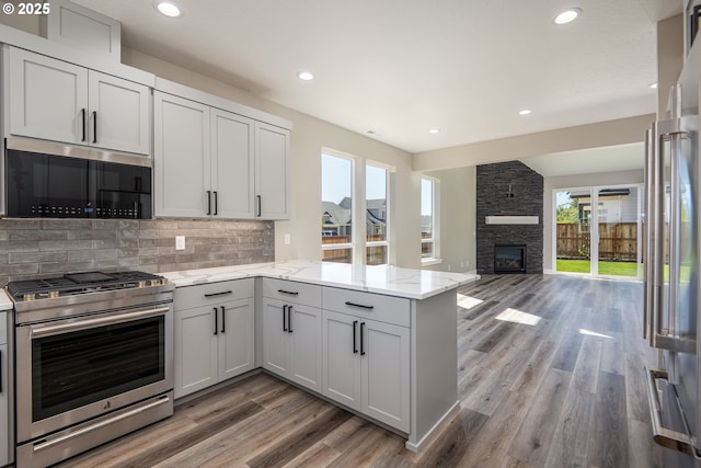 24934 Westfield Ave, Veneta, OR 97487 - kitchen with appliances with stainless steel finishes, a peninsula, light wood-style flooring, tasteful backsplash, and light stone counters