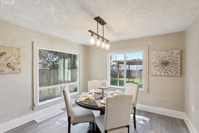 dining room with visible vents, a textured wall, and wood finished floors