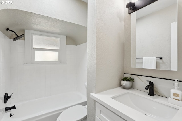 full bath with a textured wall,  shower combination, vanity, and toilet