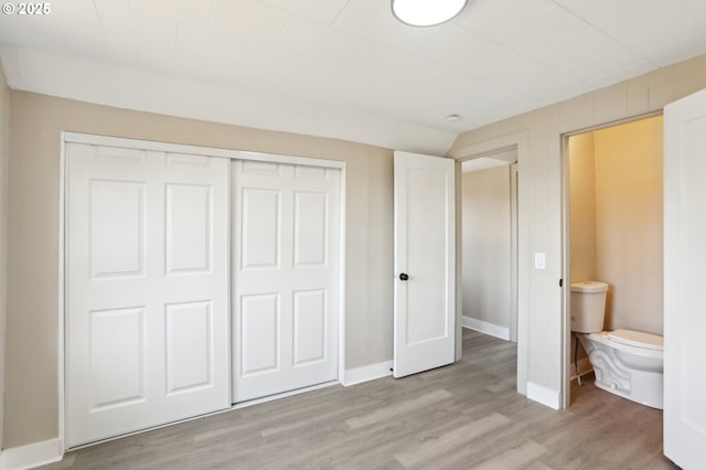 unfurnished bedroom featuring light wood-style floors, baseboards, and a closet