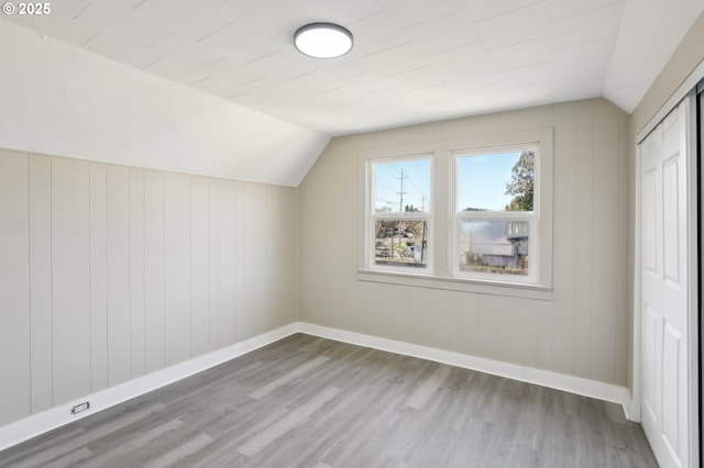 additional living space with baseboards, vaulted ceiling, and wood finished floors